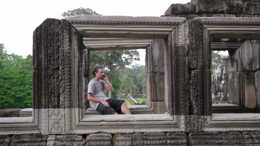 Caucasian man tourist talking with mobile phone in Angkor