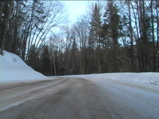Low angle view of a car driving through remote area with roads filled with snow