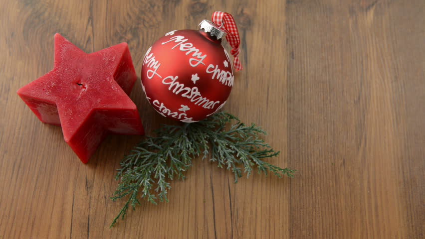 Christmas candle in star shape is lit with a match. In addition, a fir twig lies with a Christmas ball with the words "Merry Christmas". 