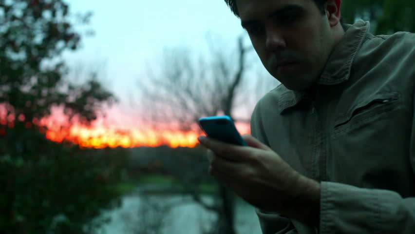 overworked man turns off smart phone to look at the sunset. Natural lighting