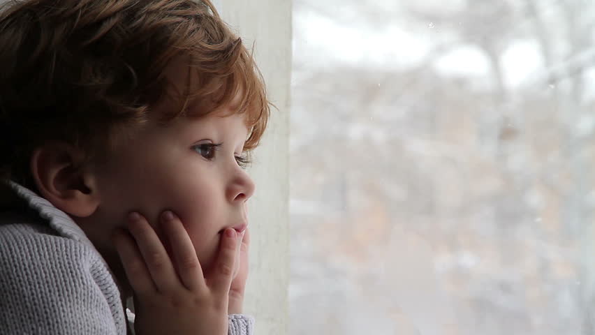 Boy looking out the window at the falling snow