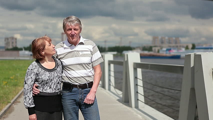 Happy mature couple walking on the Neva river embankment under the Cable Bridge, St. Petersburg
