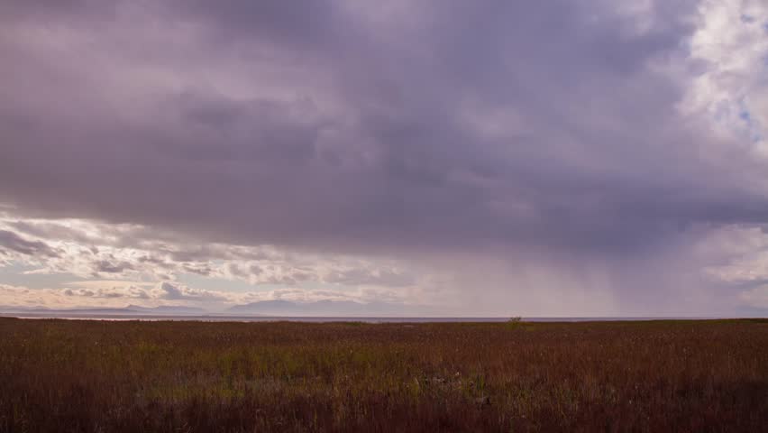 Time Lapse of Rainy Clouds in a Distance with Sun Shinning behind the Clouds.Shot in 4k RAW photo sequence