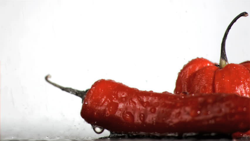 Spicy vegetables in super slow motion being wet against a white background