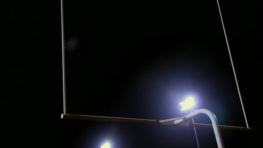 Multiple shots of a stadium lights shinning on a goalpost in a football field.