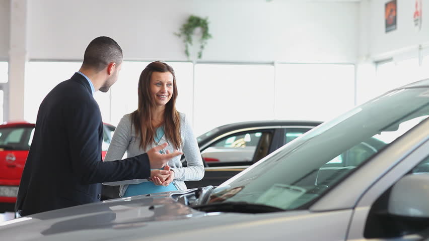 Businessman showing a car to a woman in a dealership
