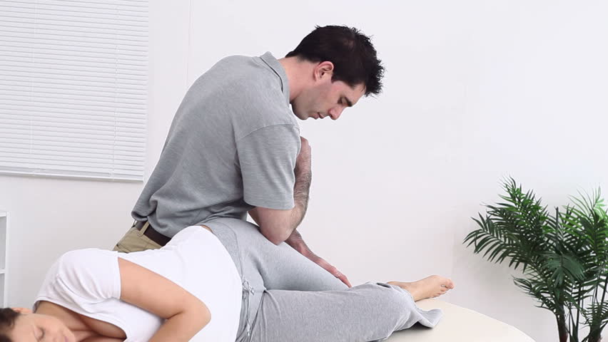 Physiotherapist using his elbow to massage the thigh of a woman in a therapy room
