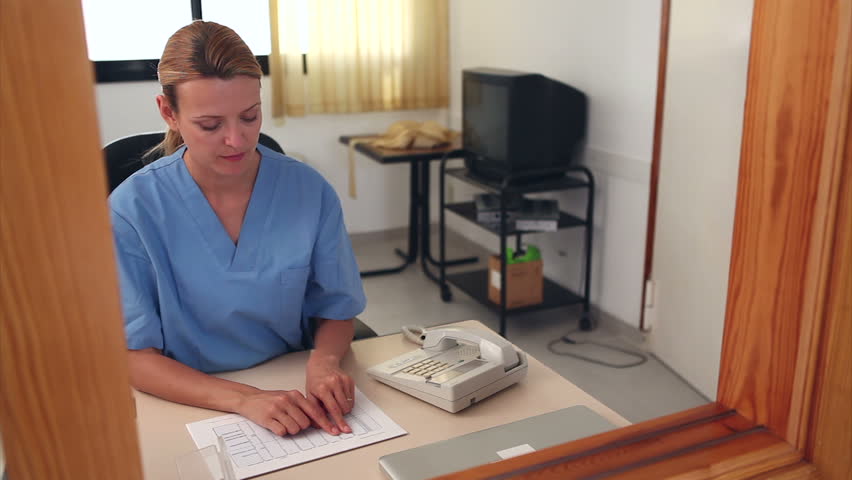 Nurse looking at files at a reception desk in a hospital
