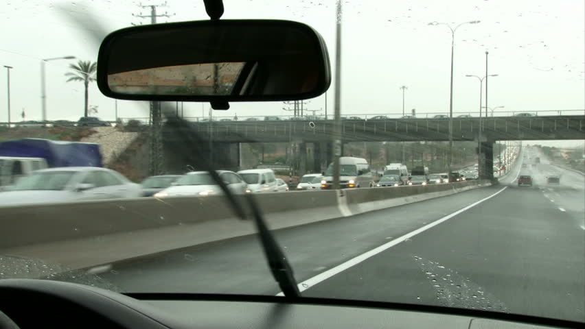 Driving on highway on a rainy day. Hand on steering wheel Point of view