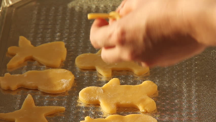Baking Sugar Cookies 15. Preparing, mixing, baking and decorating Christmas sugar cookies. Placing prepared cookies of different shapes onto a cookie sheet.