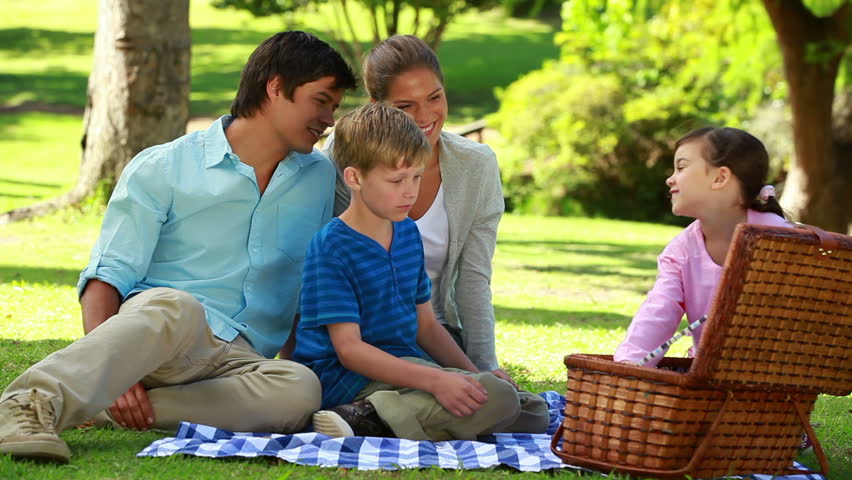 Happy family sitting on a blanket during a picnic in a parkland