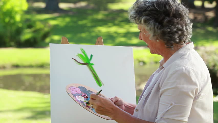 Mature woman painting on a canvas in the countryside