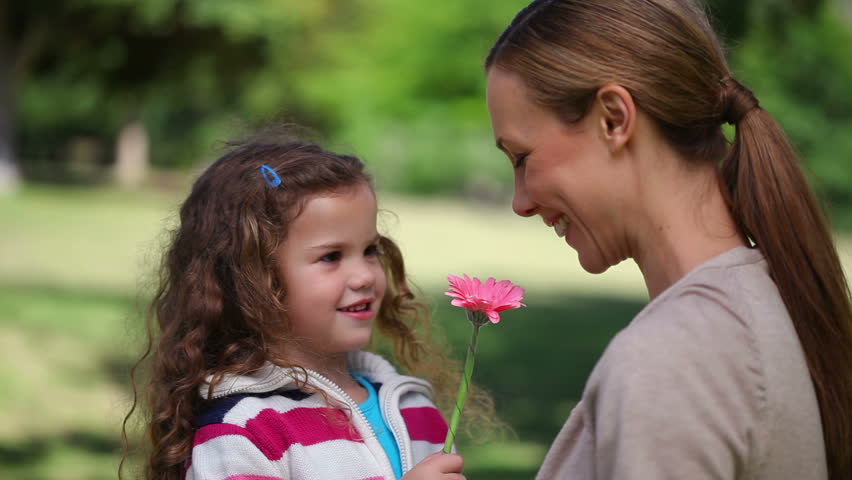 Mother smelling a flower holding by her daughter in a park