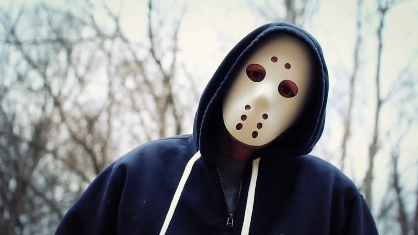 A masked killer hovers over his victim on a wintery forest trail.