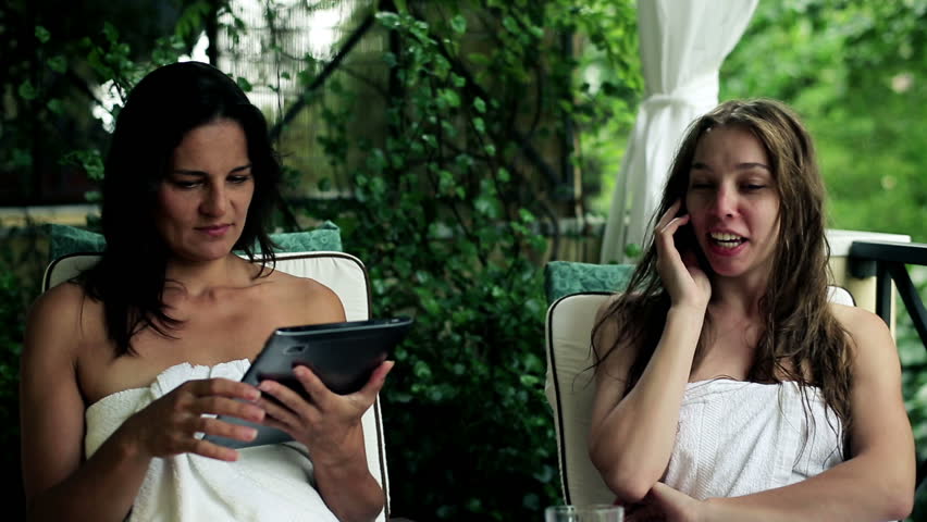 Two women with tablet and cellphone relaxing on balcony, stabilized shot
