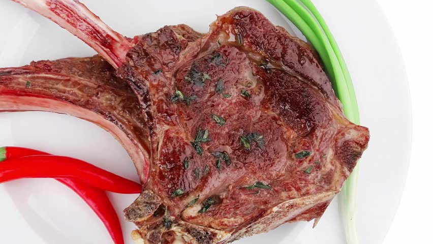 meat savory : grilled beef ribs served with green chives and raw red chili peppers on white dish isolated over white background