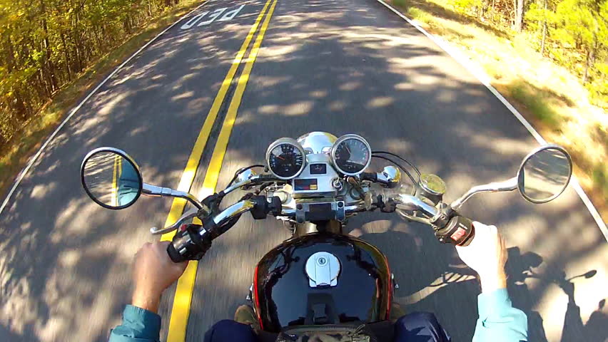 A shot of the handlebars, gages and gas tank of a speeding motorcycle as seen from a high angle helmet cam.