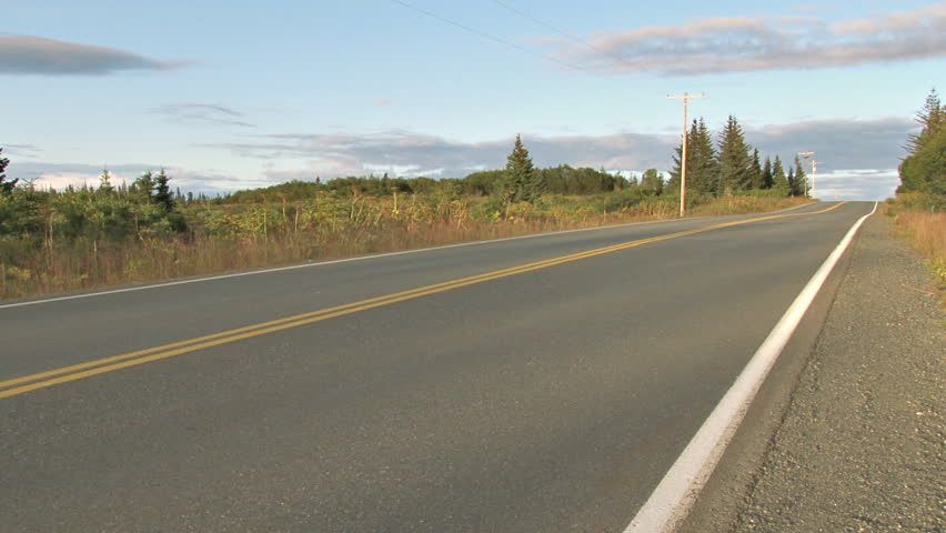 White pickup truck drives by on paved road in evening.