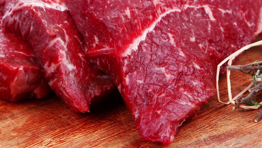 fresh raw beef meat fillet flesh with peppercorn and thyme ready to grill on wood figured old style board isolated over white background