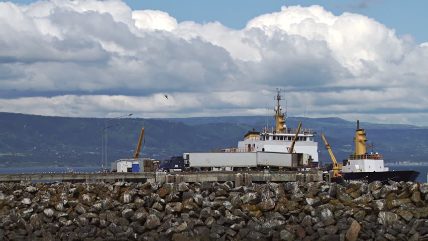 A semi tractor-trailer hauls fish along the deepwater dock pier road to the processing plant on the Homer Spit from a large fishing tender that brought fish from fishing vessels at sea into port.