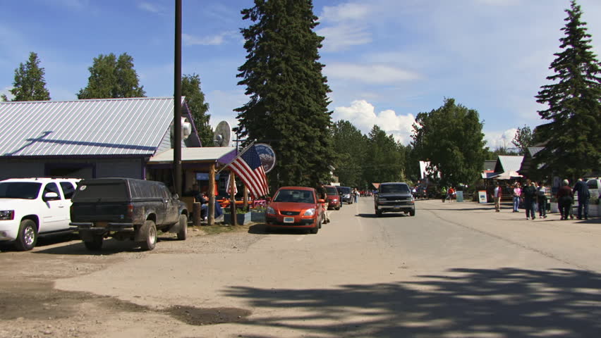 TALKEETNA, AK - CIRCA June 2012: A pickup truck passes to reveal wandering tourists and the famed Talkeetna Roadhouse.