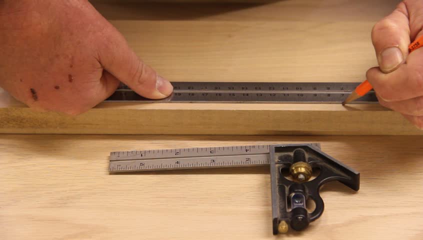 carpenter measures an marks a board with a tri square