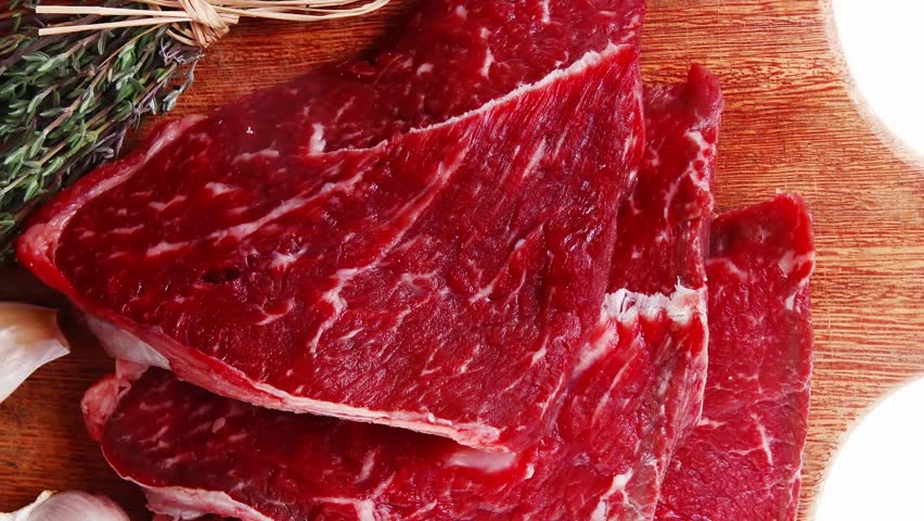 fresh raw beef meat fillet flesh with peppercorn and thyme ready to grill on wood figured old style board isolated over white background