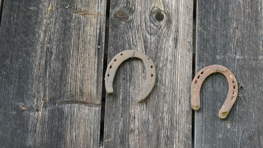 Hand hang retro rusty horse shoe on rural house wall.