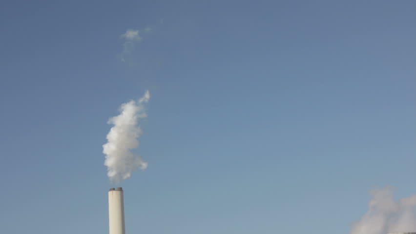 tall slender cooling tower releasing a plume of water vapor on a blue sky