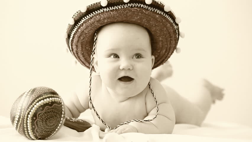 Baby in sombrero hat with maracas on the light background