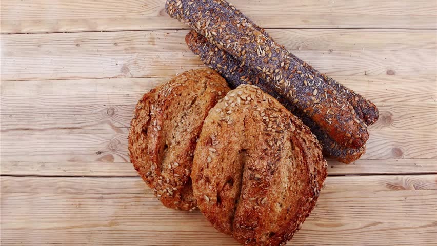 delicacy french rye breads and baguettes topped with sunflower and poppy seeds over wooden table