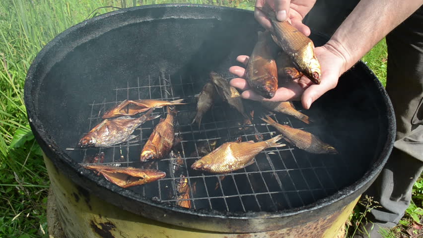 man hand take fresh delicacy smoked fish from smokehouse.