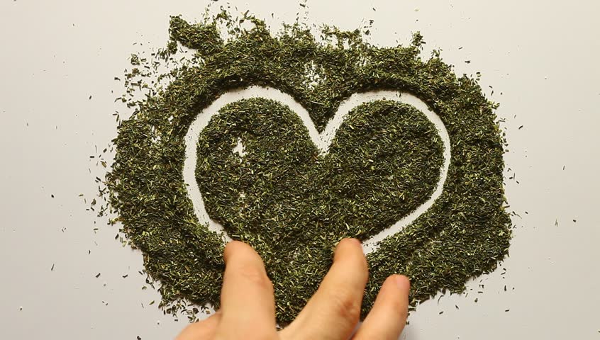 Young adult woman makes Valentines heart out of dry dill.
