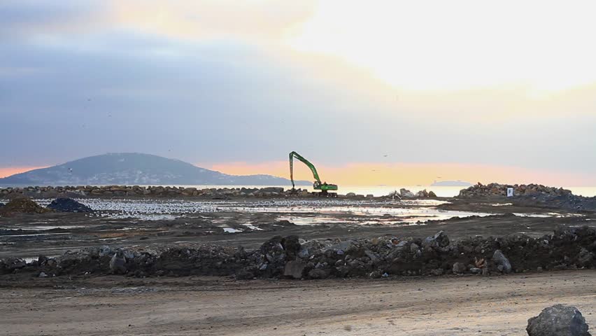 Heavy duty transfer dump truck carrying lots of stuff on the construction site. Trucks and a hydraulic excavator working for formation of new land by filling the sea. Hauls things as gravel or rock 
