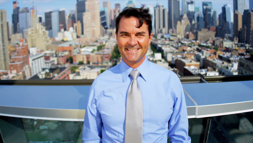 Portrait of attractive Caucasian businessman on rooftop overlooking Manhattan 