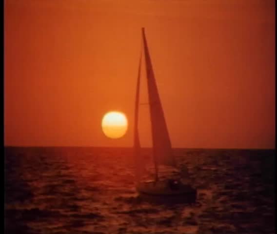Tranquil scene of sailboat drifting at sea at sunset