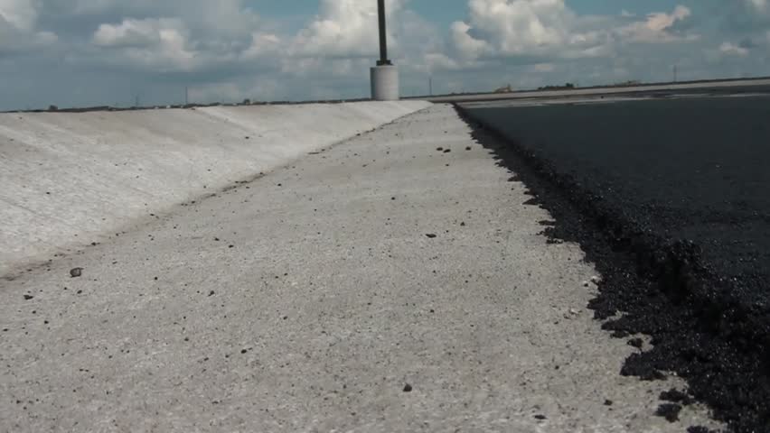 Rolling a measuring wheel ahead and back to camera with heat emitting from blacktop.