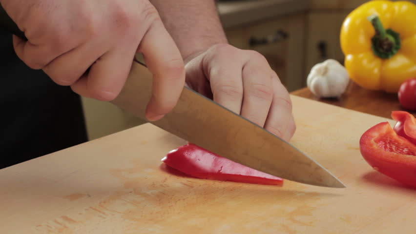 Chef cutting up red pepper with a knife