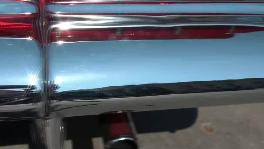 Panning across shiny chrome bumper in sunshine on a classic 50's car.