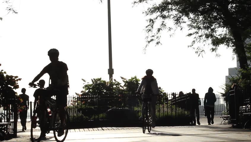 People in silhouette walk on the Brooklyn Heights Promenade