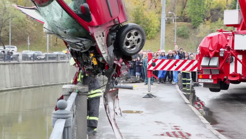 MOSCOW - OCT 9: EMERCOM serviceman takes part of crashed car which hangs on crane at quay of Yauza river, Oct 9, 2011, Moscow, Russia.