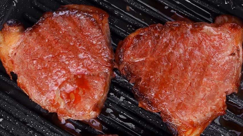 roast bloody beef fillet steaks on black teflon grill plate hidef slow motion intro