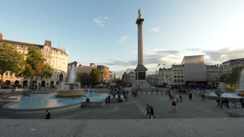 Tilt shot of Trafalgar Square - fountains, people, and Lord Nelson's monument - which is then all hidden behind small column structure. 