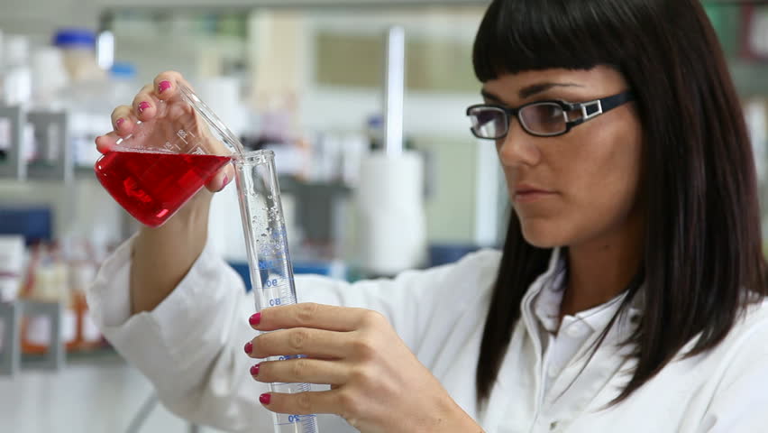 Female Scientist examining a beaker of fluid. Focus on the scientist.