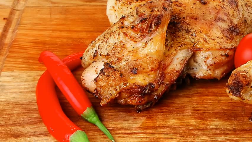 meat food : roasted chicken legs garnished with green sprouts and peppers on wooden plate hidef slow motion intro