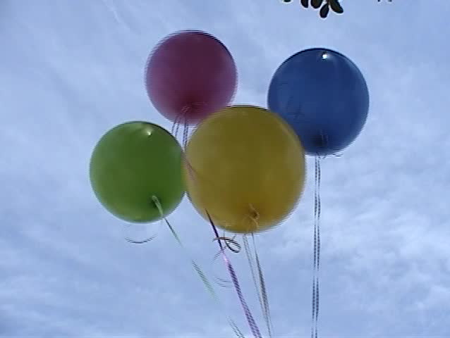 5 helium balloons float away in the wind against a blue spring sky