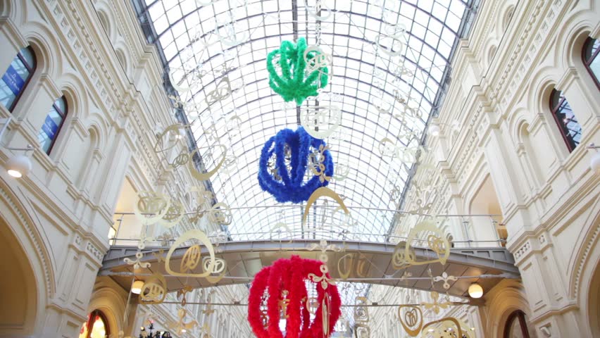 Interior of GUM embellished with decorations that hang with glass roof. People are doing Christmas shopping in the GUM (department store). GUM is a famous shop on Moscow's Red Square.