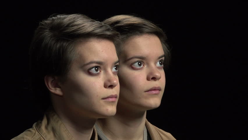 Twin sisters looking at each other with arm around shoulder