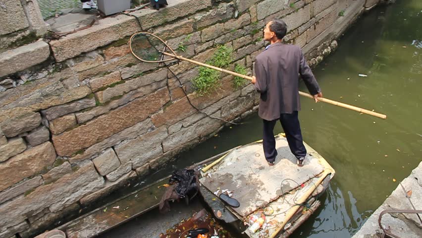 SUZHOU - APRIL 29: Worker cleaning a canal on April 29, 2011, in Suzhou, China. The city is very clean and well preserved and it is famous by its beautiful canals, architecture and gardens.