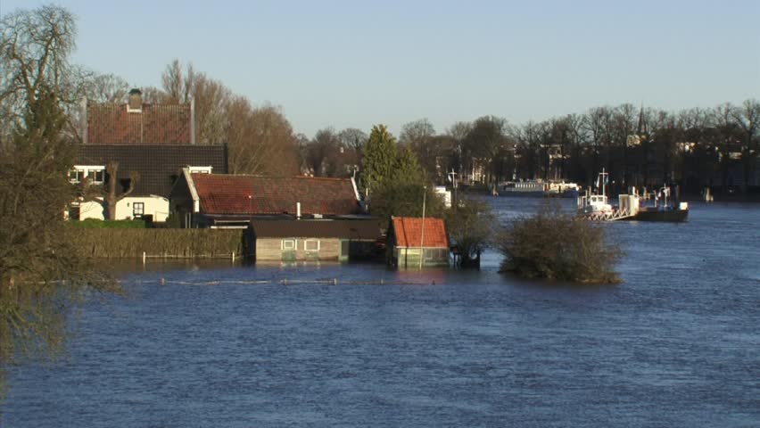 View of drowned houses in inundated flood meadow due to high water level in river IJssel, The Netherlands. Ferry boat in background.